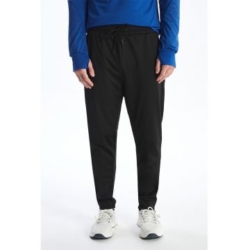 Pantaloni de trening cu croiala conica si buzunare cu fermoar
