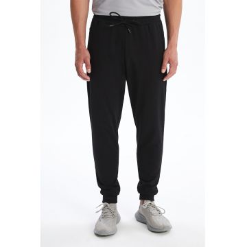 Pantaloni de trening cu croiala conica si buzunare cu fermoar